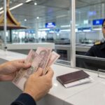 Traveller counting Thai baht at a Thai airport immigration counter