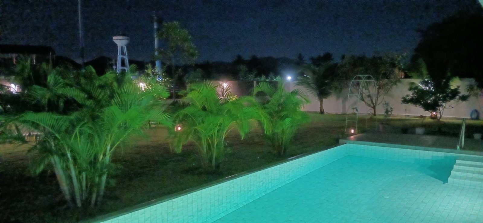 Illuminated private pool and tropical garden at night
